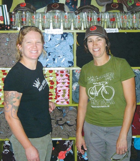 Anne Keller, left and Jen Zeuner are surrounded by the t-shirts, hats and other merchandise they sell at the Hot Tomato in Fruita. The most popular products at the restaurant, though, are the handcrafted pizzas and salads. (Business Times photo by Phil Castle)